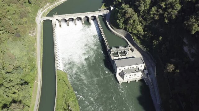 Aerial view of an historic hydroelectric power plant located on a river bank, which exploits the difference in height created by the dam on the Adda river, Italy