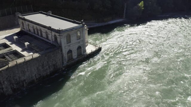 Aerial view of an historic hydroelectric power plant located on a river bank, which exploits the difference in height created by the dam on the Adda river, Italy