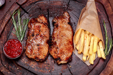 Fried meat with spices and vegetables on a wooden board. European cuisine.