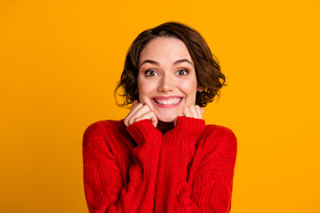 Closeup photo of funny excited lady good mood toothy smile hands under cheeks short bob hairdo wear casual red knitted sweater isolated vivid bright yellow color background