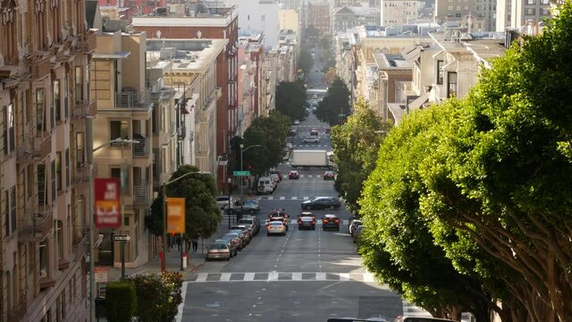 Iconic hilly street and crossroads in San Francisco, Northern California, USA. Steep downhill road and pedestrian walkway. Downtown real estate, victorian townhouses abd other residential buildings.