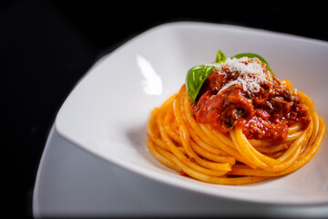 Spaghetti al sugo con formaggio e basilico fotografati in un piatto bianco