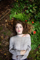 Gothic portrait. The girl lies on the grass. Girl in fern and amanita.