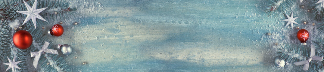 Christmas background with fir twigs, light green and red trinkets and silver stars on light background, space