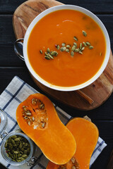 Top view of pureed pumpkin soup in a white bowl on dark table