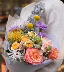 Flower shop. Beautiful bouquet of mixed flowers in woman hand. the work of the florist at a flower shop. Delicate Pastel color. Fresh cut flower.