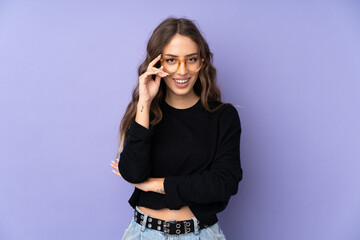 Young woman over isolated purple background with glasses and happy