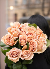Young woman with a gift bouquet of cappuccino roses, mono bouquet of roses. Young woman holding...