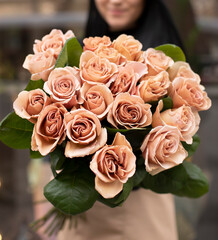 Young woman with a gift bouquet of cappuccino roses, mono bouquet of roses. Young woman holding fresh bouquet of roses.