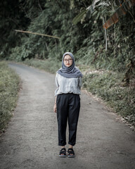 Beautiful Asian Muslim woman posing and stylish with rice fields and trees as background.