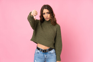 Young woman over isolated pink background showing thumb down with negative expression
