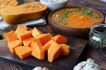 Cut pieces of raw pumpkin on wooden board on table