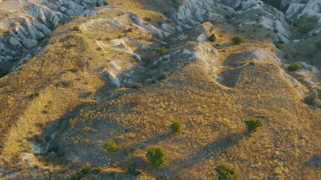 Amazing view in valley of Turkish mountains of Cappadocia and rock formations. Impressive forms of sandstone at sunset. Picturesque landscape of territory of National Park Goreme from drone