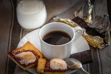 White cup of coffee with cookies, a glass of milk and chocolate. Morning breakfast.