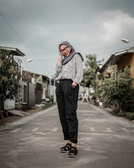 Beautiful Asian Muslim woman is standing posing and stylish in the middle of a luxury residential street.