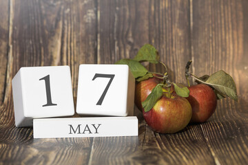 May 17. Day 17 of month. Calendar cube on wooden background with red apples, concept of business...