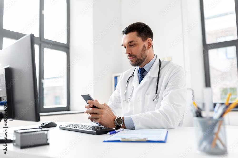 Poster healthcare, medicine and people concept - male doctor with smartphone at hospital