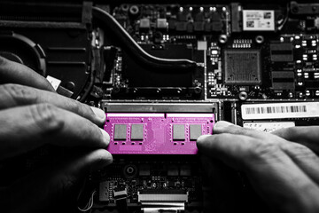 Close-up on the pink RAM memory that the hands of the service technician insert into the slot on...