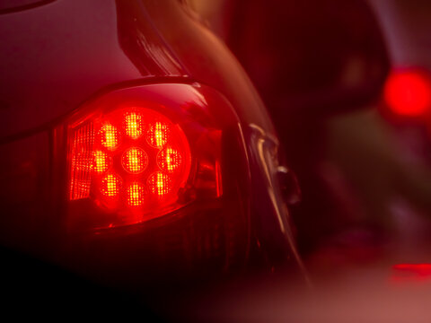 Rear lights of the car. Red brake lights. Colorful background or texture. Copy space. Selected focus