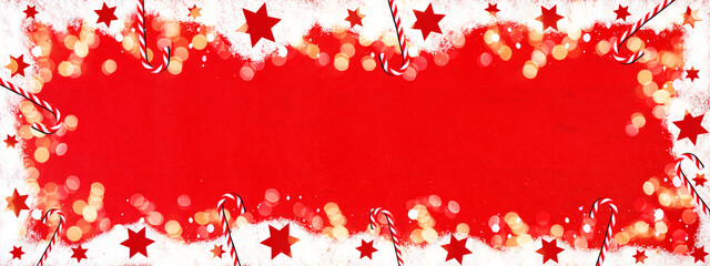 Christmas / winter background banner panorama template - Frame made of snow with snowflakes, stars, candy canes and bokeh lights on red colored wooden texture, top view with space for text