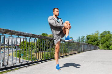 fitness, sport and healthy lifestyle concept - man stretching leg on bridge
