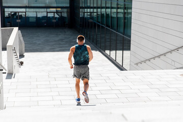 Fototapeta na wymiar fitness, sport, training and lifestyle concept - young man in headphones running downstairs outdoors