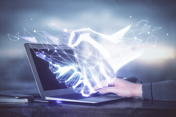 Handshake hologram drawing with businessman working on computer on background. Double exposure.