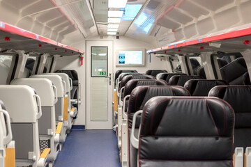 Inside the train wagon. Empty comfortable black leather chairs in a modern electric  train. 