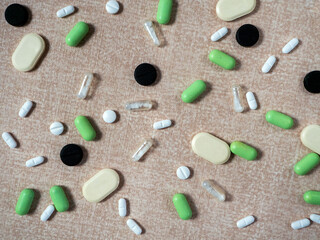 Beige background with medicines separately. Medical background with pills for different diseases, different shapes and colors.