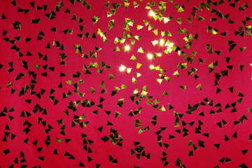 Festive red background. Shining gold confetti in form of new year tree. Christmas and New Year celebration. Flat lay, top view, copy space.