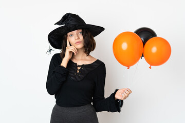 Young witch holding black and orange air balloons thinking an idea