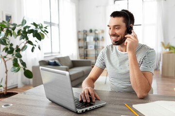 remote job, technology and people concept - happy smiling man with headset and laptop computer having video conference at home office