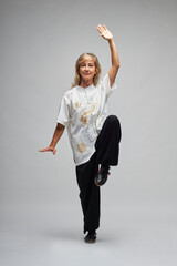 Mature blonde woman practicing Chi kung and Tai Chi on a white background. She wears a traditional white chinese Tai Chi jacket, black trousers and black shoes with ying yang symbol