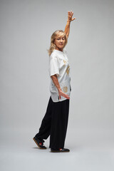 Mature blonde woman practicing Chi kung and Tai Chi on a white background. She wears a traditional white chinese Tai Chi jacket, black trousers and black shoes with ying yang symbol