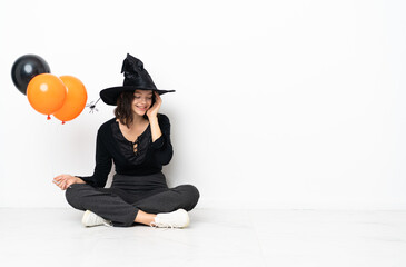 Young witch holding black and orange air balloons sitting on the floor laughing