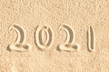 Year 2021 written in the sand of a beach, new year card