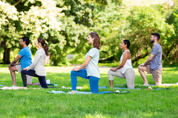 Fototapeta premium fitness, sport and healthy lifestyle concept - group of happy people doing yoga at summer park