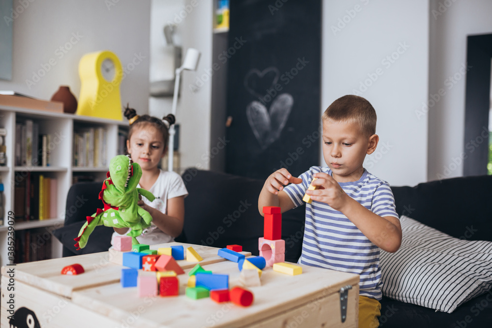 Wall mural brother and sister playing with play cubes at home