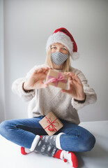 young, pretty woman with Corona mask and red Christmas cap is waiting for christmas