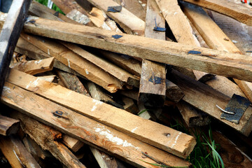 lots of old brown boards after use with metal nails driven in and white paint side view