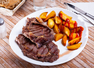 Tasty homemade baked beef fillet served with fried potato wedges and ketchup