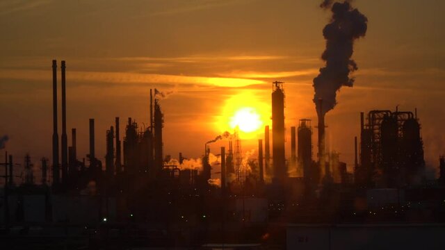 Smoking pipes of an oil refinery in the backlight of the sunset.