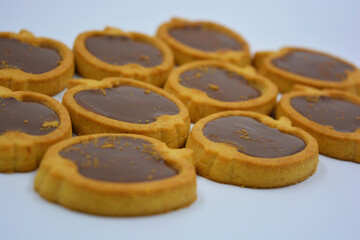 Fresh delicious crunchy shortbread cookies with nutty, chocolate filling inside. Apple-shaped cookies with brown filling located on a white matte background.