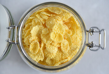 Delicious corn flakes in a glass jar on a light background