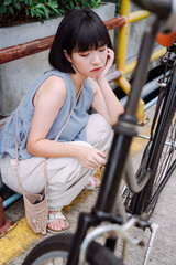 Woman sit next to the broken bicycle.