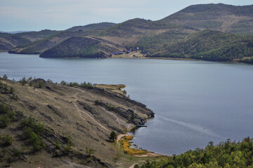 Autumn view of bay of Lake Baikal with peninsulas and mountains . Blue water, yellow and green trees. Landscape