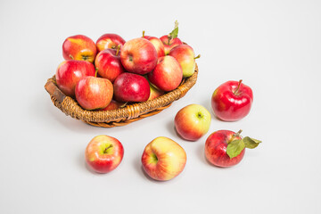 Bright multi-colored fresh apples in a wicker basket on a white background. Selective focus.