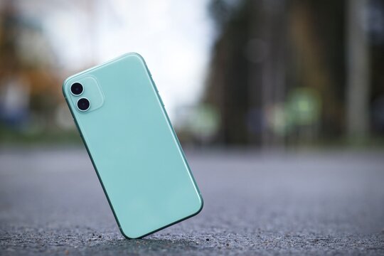 Crash test of a new shockproof mobile phone. Gadget falling and crashes on asphalt, floor. Broken smartphone flying down to the ground. Smashed, destroyed, damaged cell phone. Accident with device.