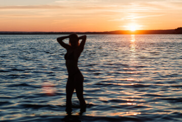 Caucasian fit woman with sport body is posing on beach at sunset time. Weight loss by the summer.