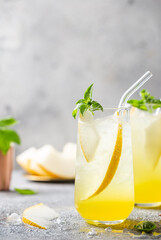 Melon juice, lemonade in glasses with ice and melon slices garnished with basil leaves. Concept of fresh summer drink